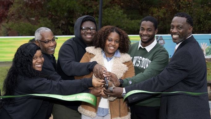 Six African American men and women cut a green ribbon