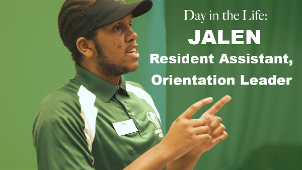 Day in the life: Jalen Resident assistant, orientation leader. A black male student wearing black sun visor and green and white polo shirt making hand gestures as if he is explaining something to someone