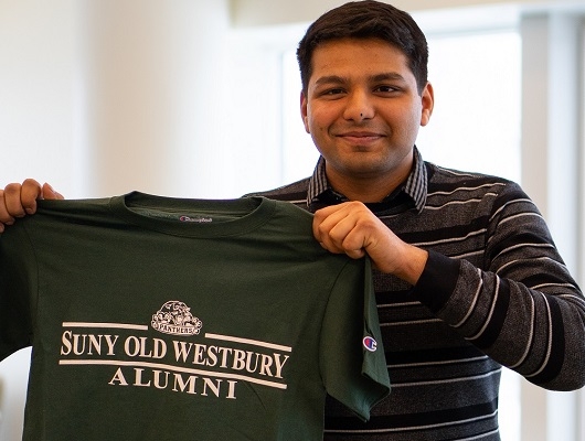 Drumil Shah holding an Old Westbury alumni t-shirt