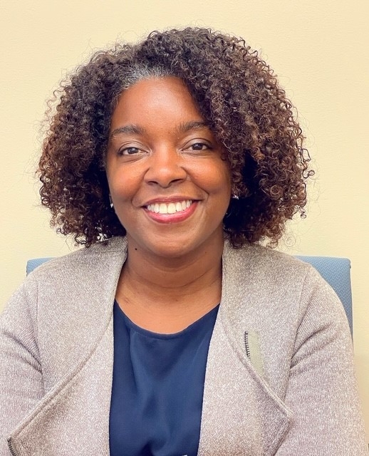 Headshot of Shalei Simms in a taupe blazer and navy shirt