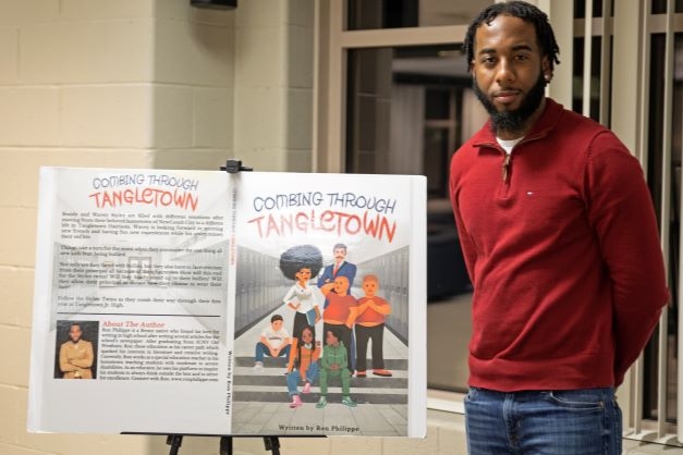 Class of 2017 graduate Ron Philippe next to his book "Combing Through Tangletown"
