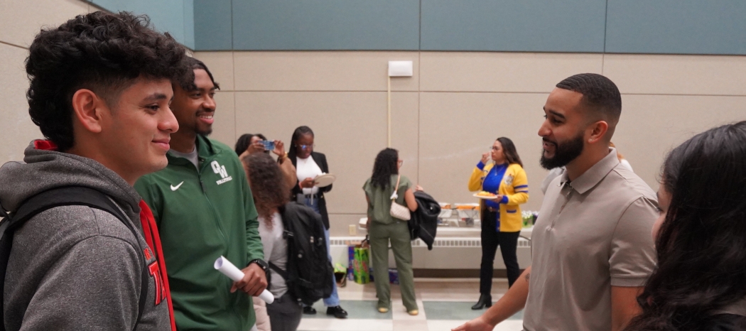 Photo of students talking with Raysel Rojas, a 2017 Finance grad and member of Lambda Alpha Upsilon