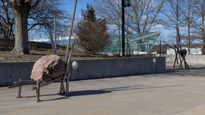 Two stone and steel scultpures on sidewalk plaza