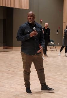 African American male stands with microphone in theater