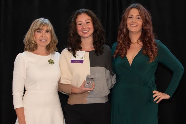 Three women posing with award