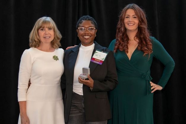 Three women pose with award