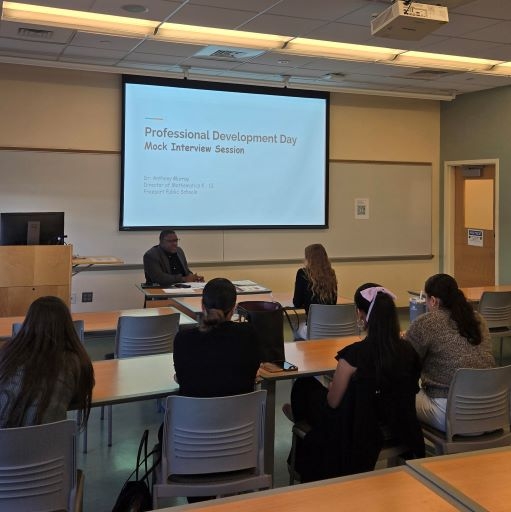 Male professor in a classroom setting leads a discussion among a diverse group of students