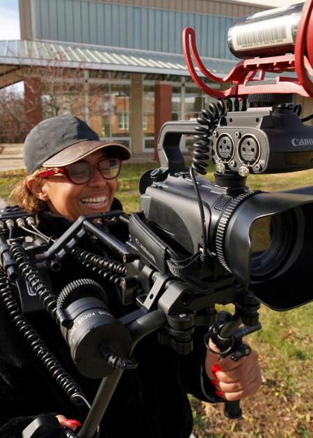 Female student wearing cap and using mobile camera rig