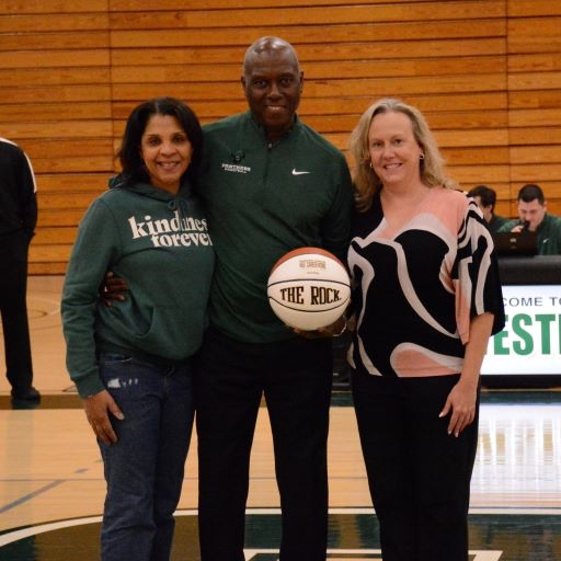 African American man holding a basketball with 450 etched on it, flanked by an African American woman and a white woman.