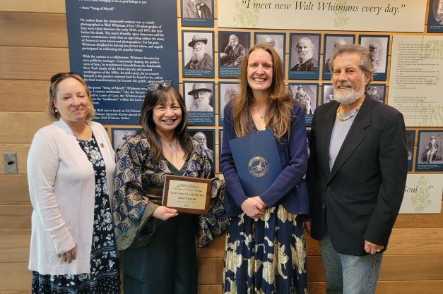 Three women and man stand during an award presentation