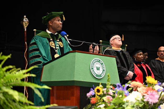 A Black man in green regalia at a podium