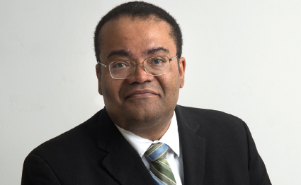 African American man with glasses in a black suit with a silver tie