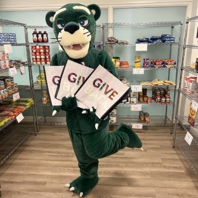 Green panther mascot holding three reusable shopping bags