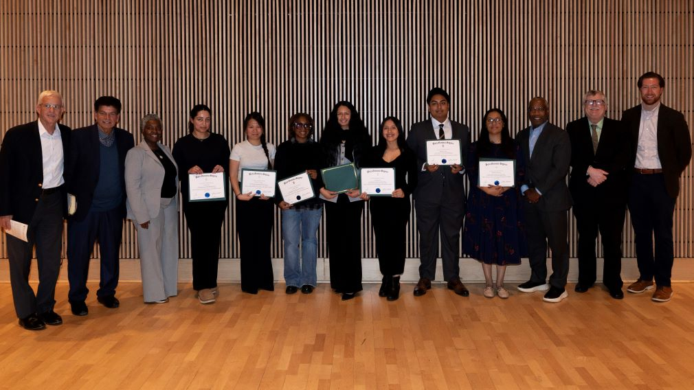 13 people in professional dress with 7 holding certificates