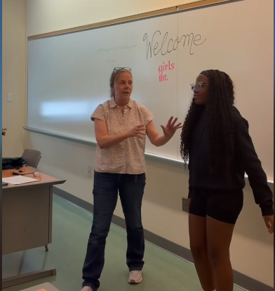 Caucasian woman and African American girl engaged in conversation in front of a whiteboard