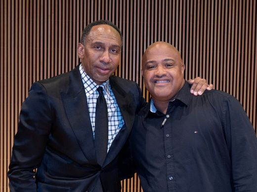 Two Black men pose with their arms around each other's shoulders