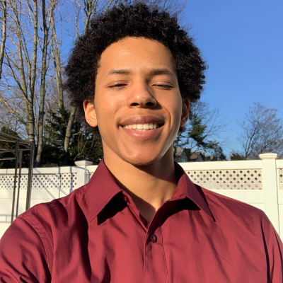 Hispanic male in maroon shirt smiles at the camera