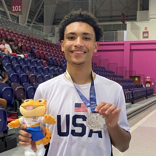African American male wearing a USA tee shirt and holding a silver medal
