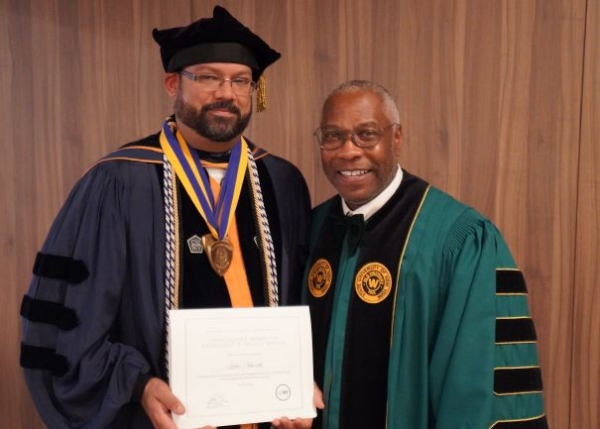 Two men in regalia pose with an award certificate