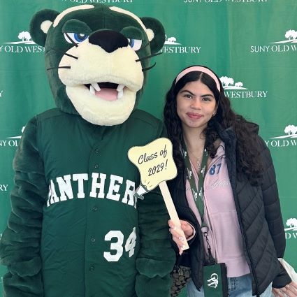 Green panther mascot stands with you woman with hair band