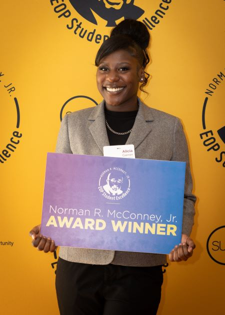 Smiling African American woman holding sign that reads McConney Award Winner