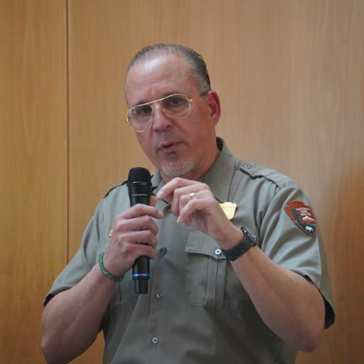 Hispanic man in park service uniform speaks into a microphone