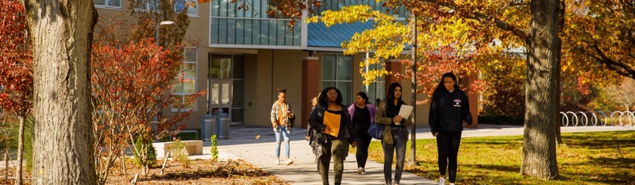 Three students walk in front of NAB on fall day