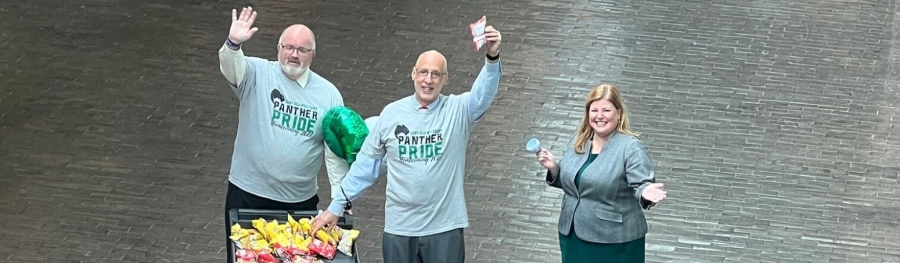 Three administrators wave at camera