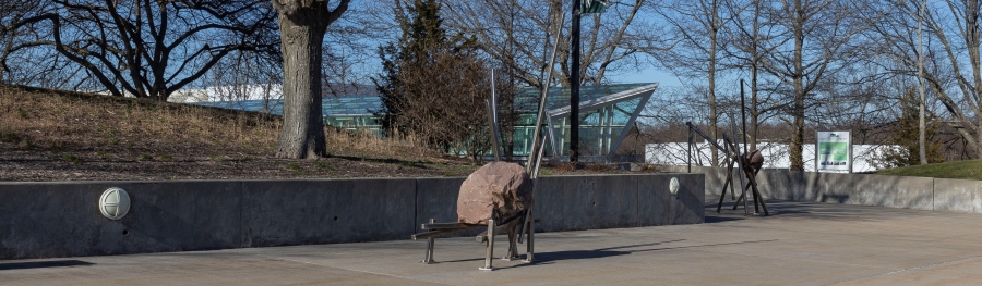 stone and steel sculpture on sidewalk plaza
