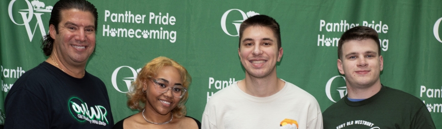 Four people in front of a homecoming banner