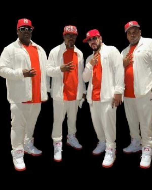 Four African American men wearing white suits, orange shirts, and matching orange baseball caps