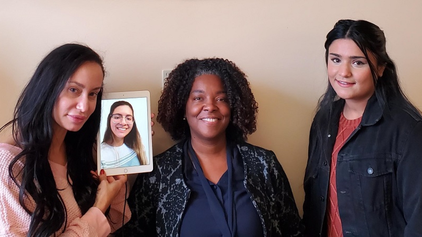 Photo of 3 students - one on a tablet screen - with the Dean of the School of Business