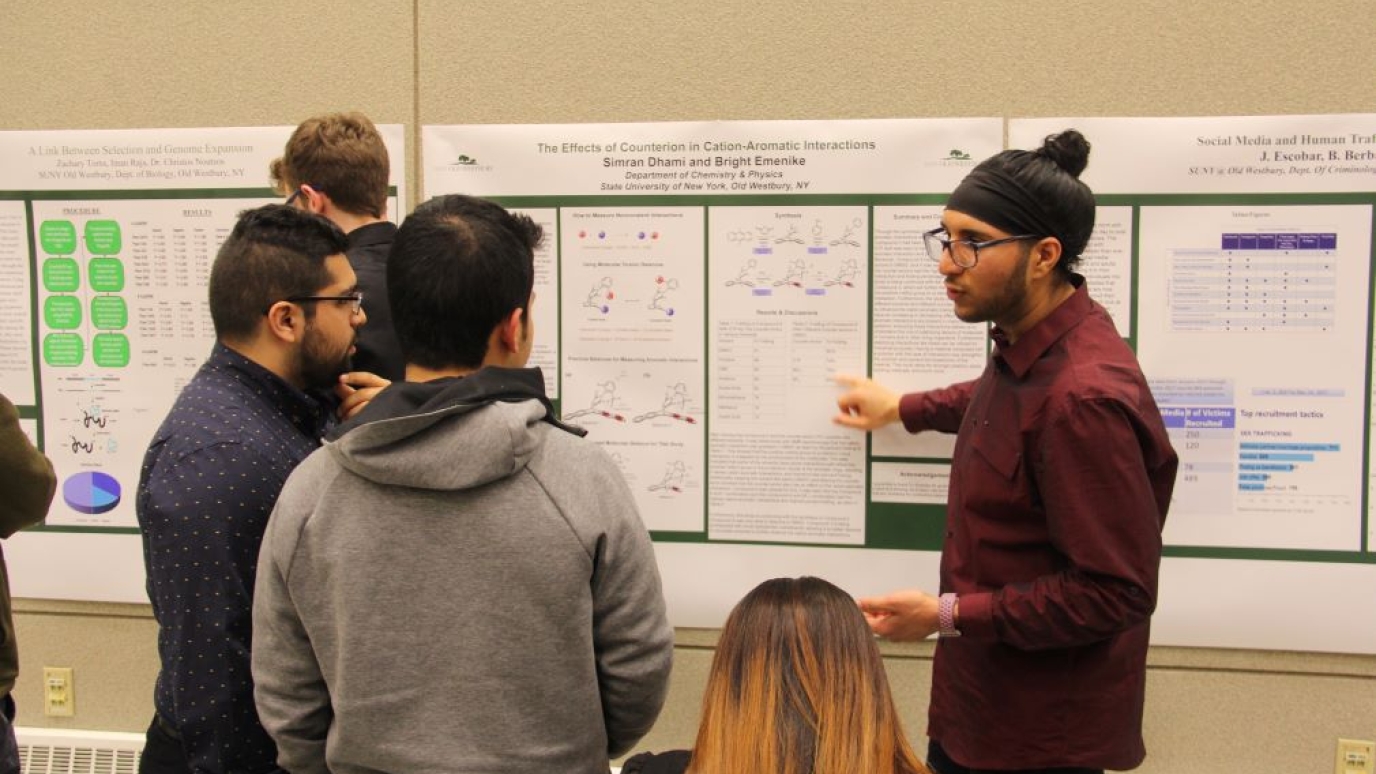Three male students reviewing a poster presentation