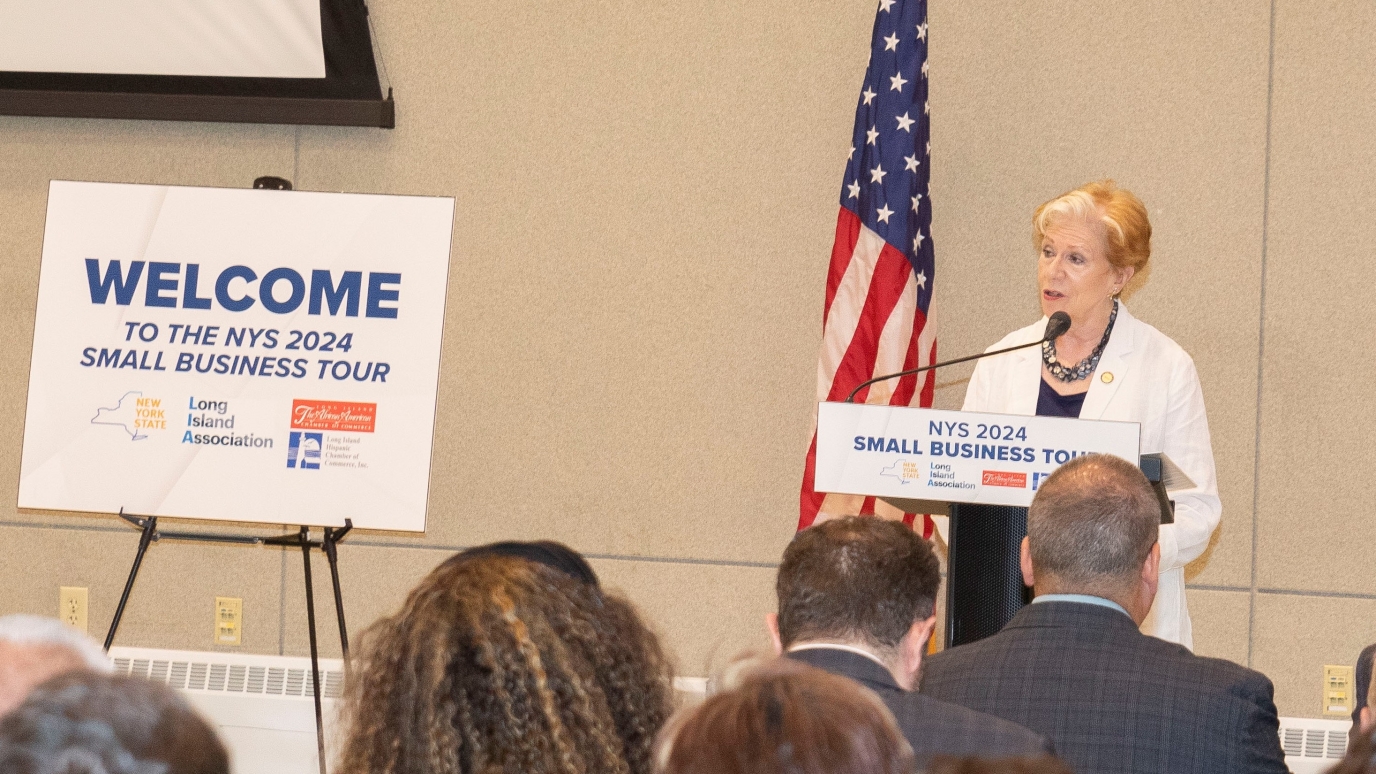 Woman at podium next to sign reading Welcome the 2024 Small Business Intragency Tour