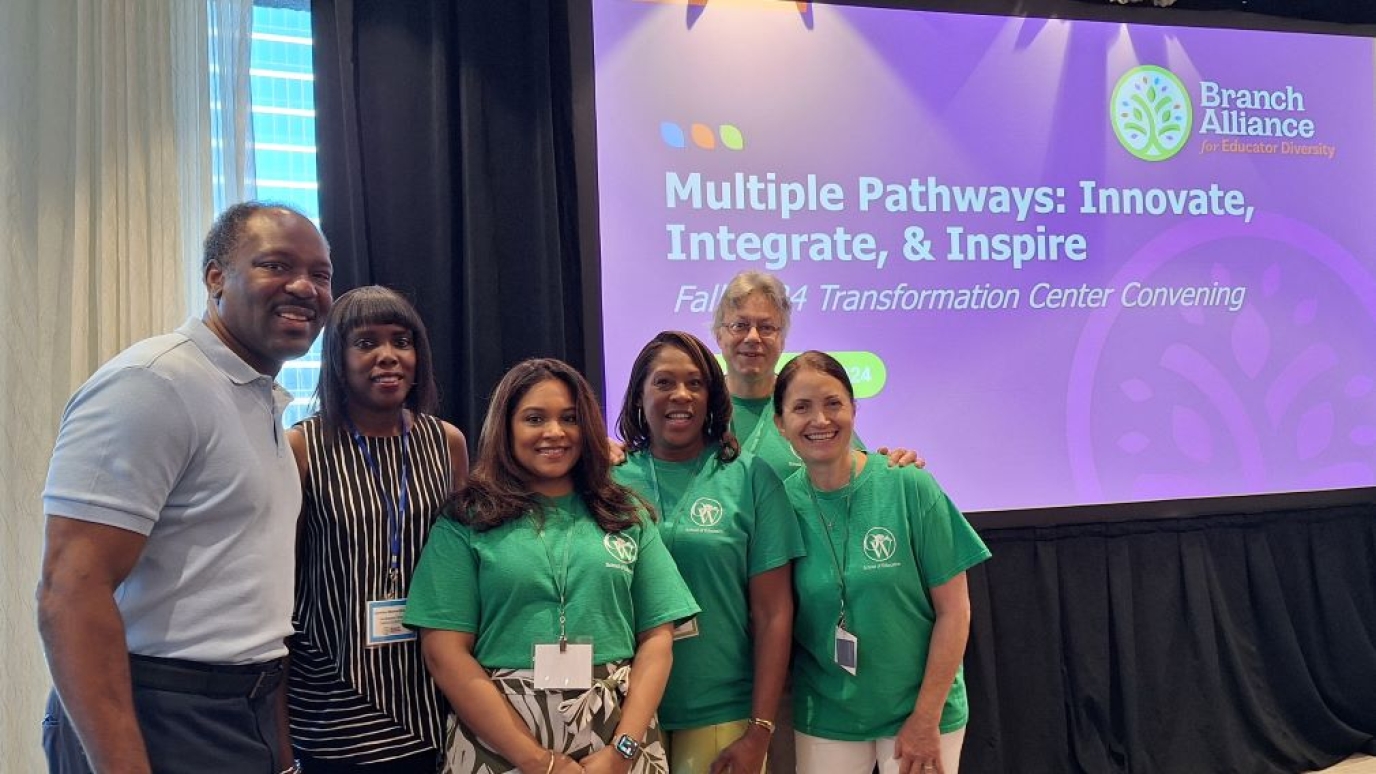 Five professionals stand before a sign reading "Multiple Pathways: Innovate, Integrate & Inspire"