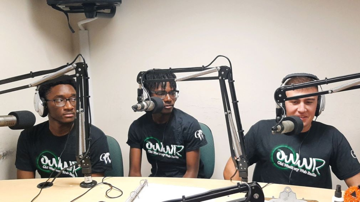Three students at microphones with headphones on