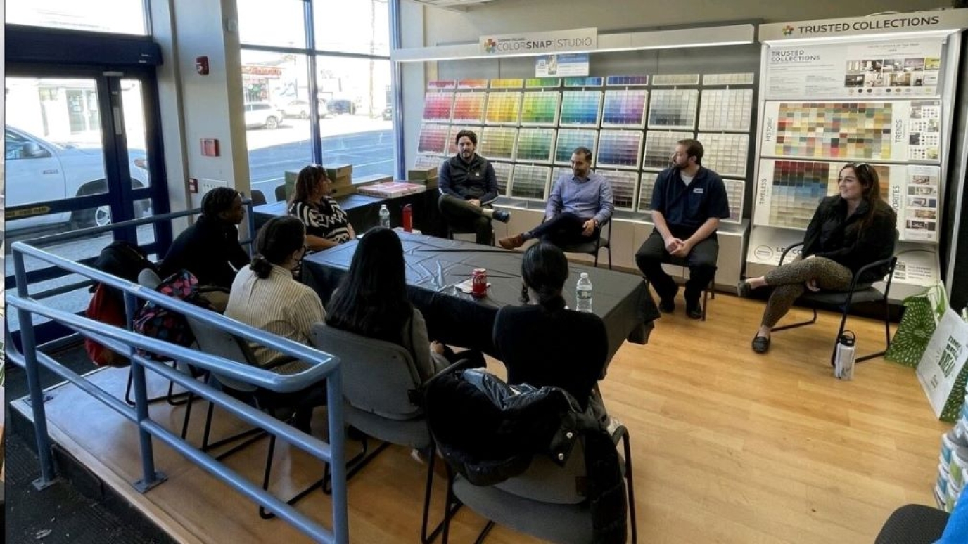 Eight people sit around a conference table talking