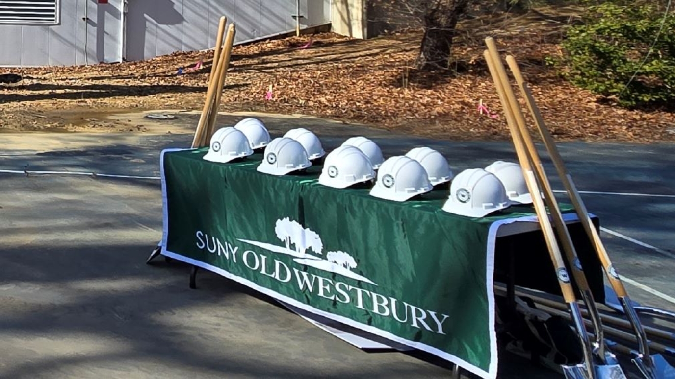 Hard hats on a table with shovels leaning against the table