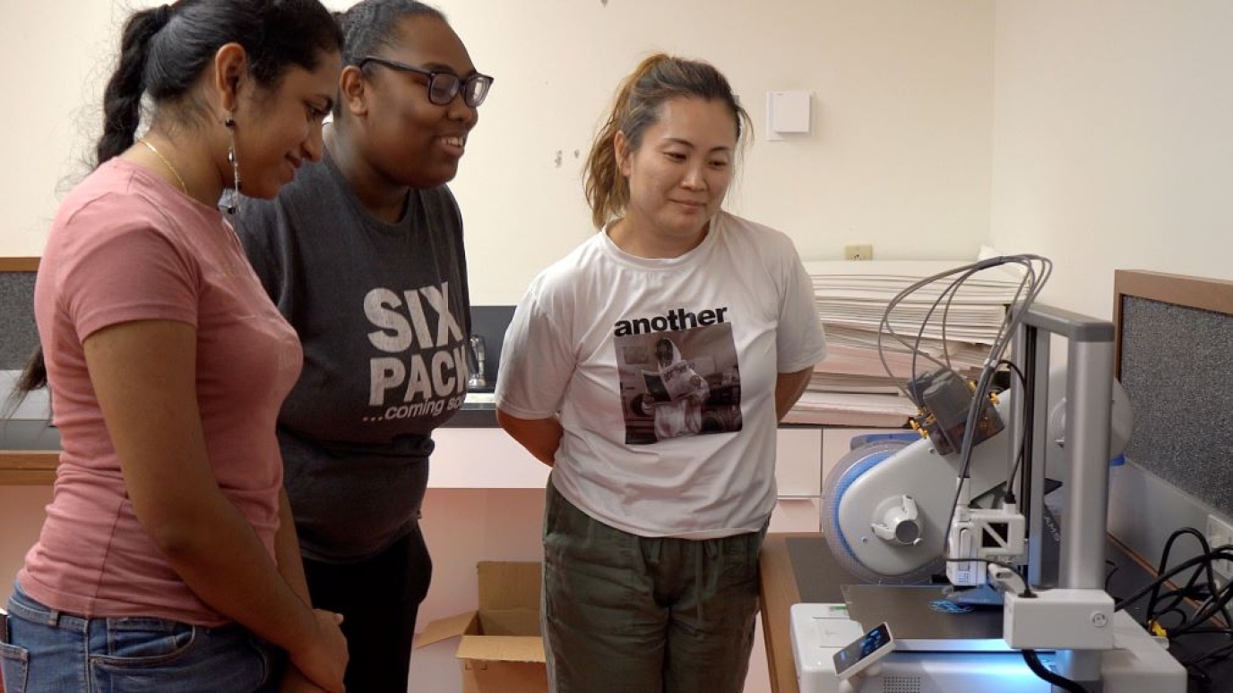 Three women working with a 3D printer