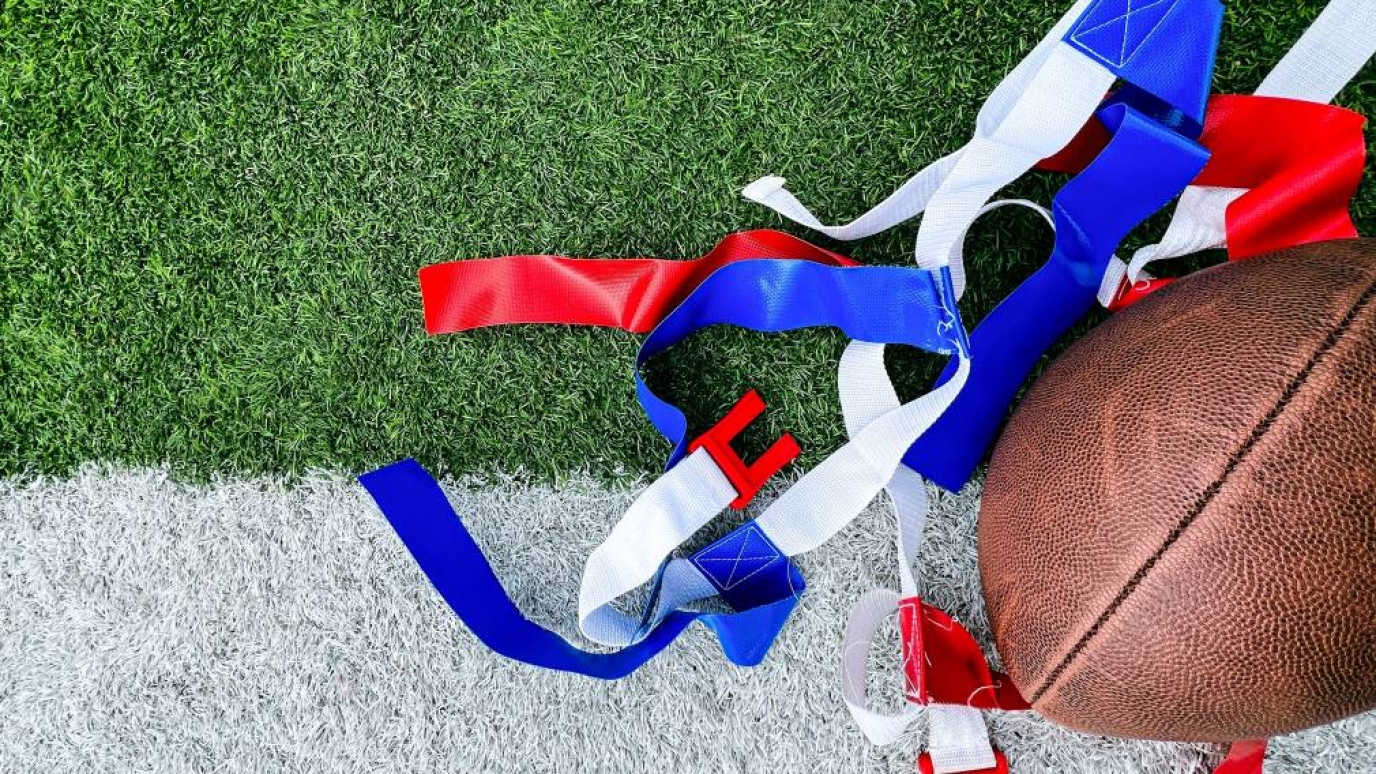 football and blue and red flags laying on a green turf field