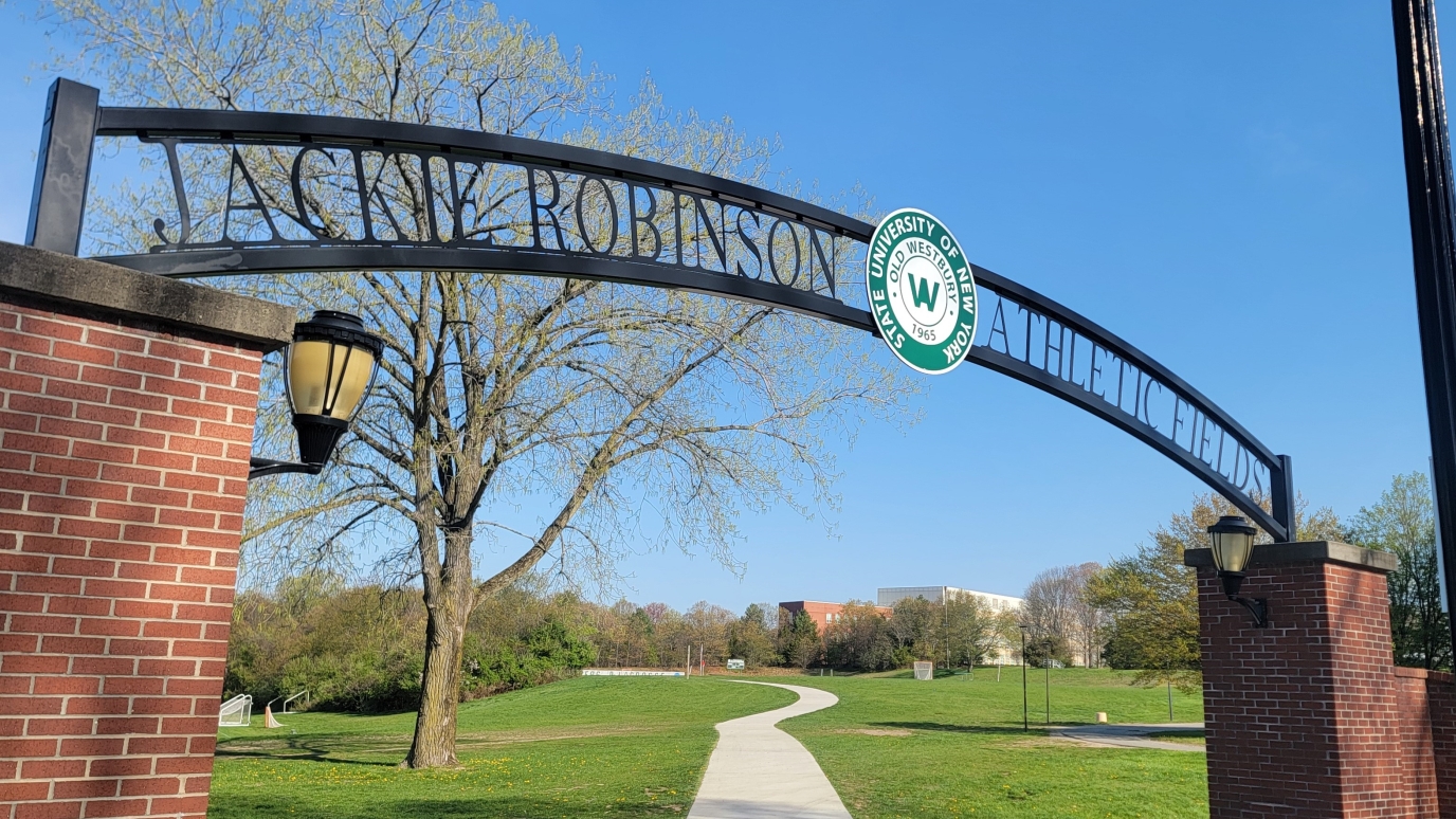 Iron  sign reading Jackie Robinson Athletic Conference hung between two brick columns.