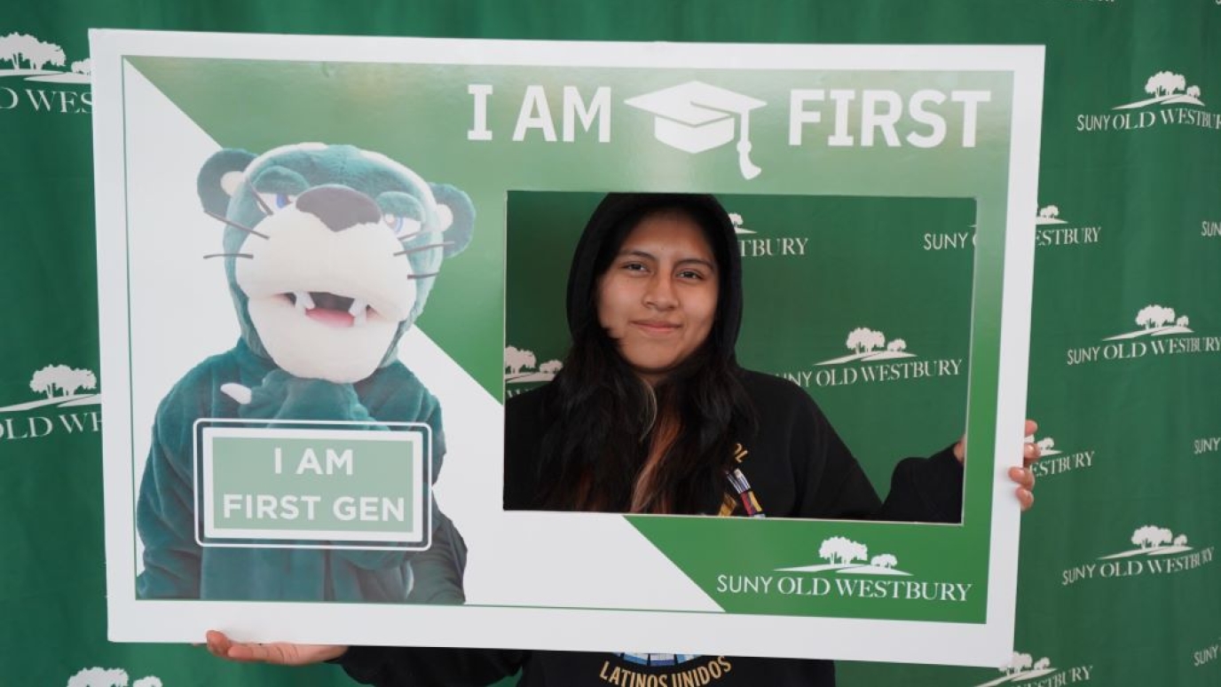Young Latina hold an "I am First Gen" poster