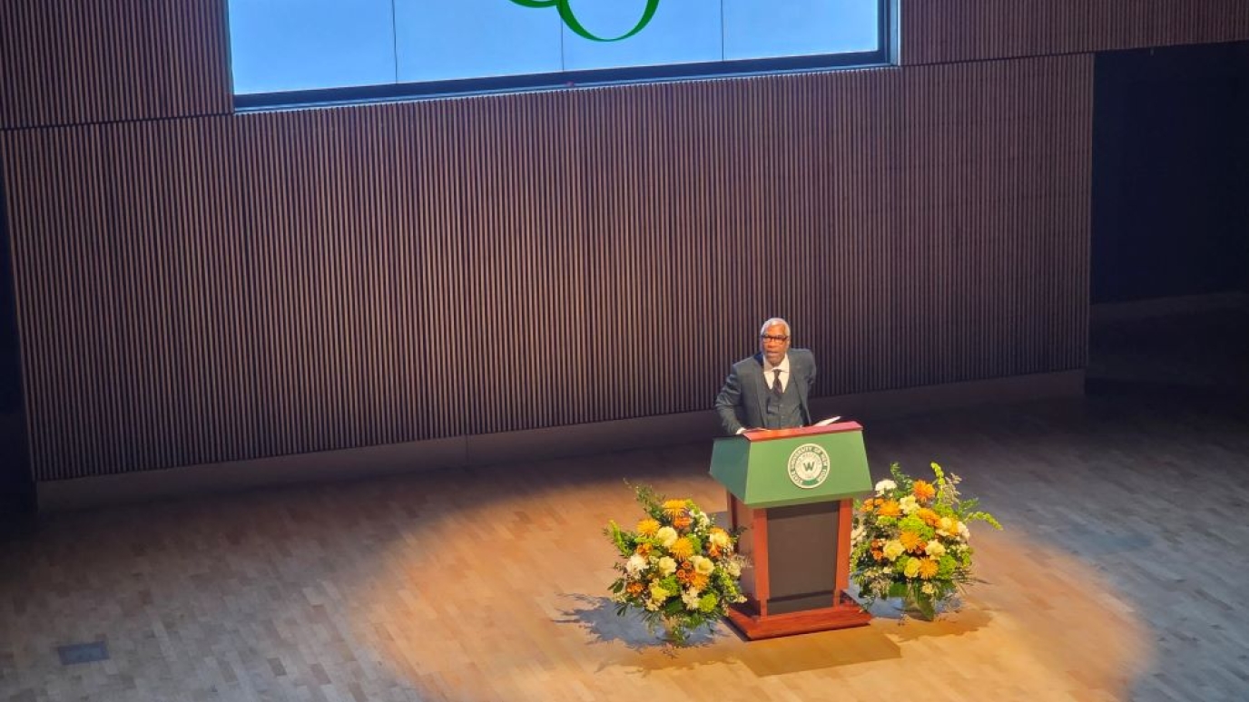 African American man giving a speech from behind a podium on stage 
