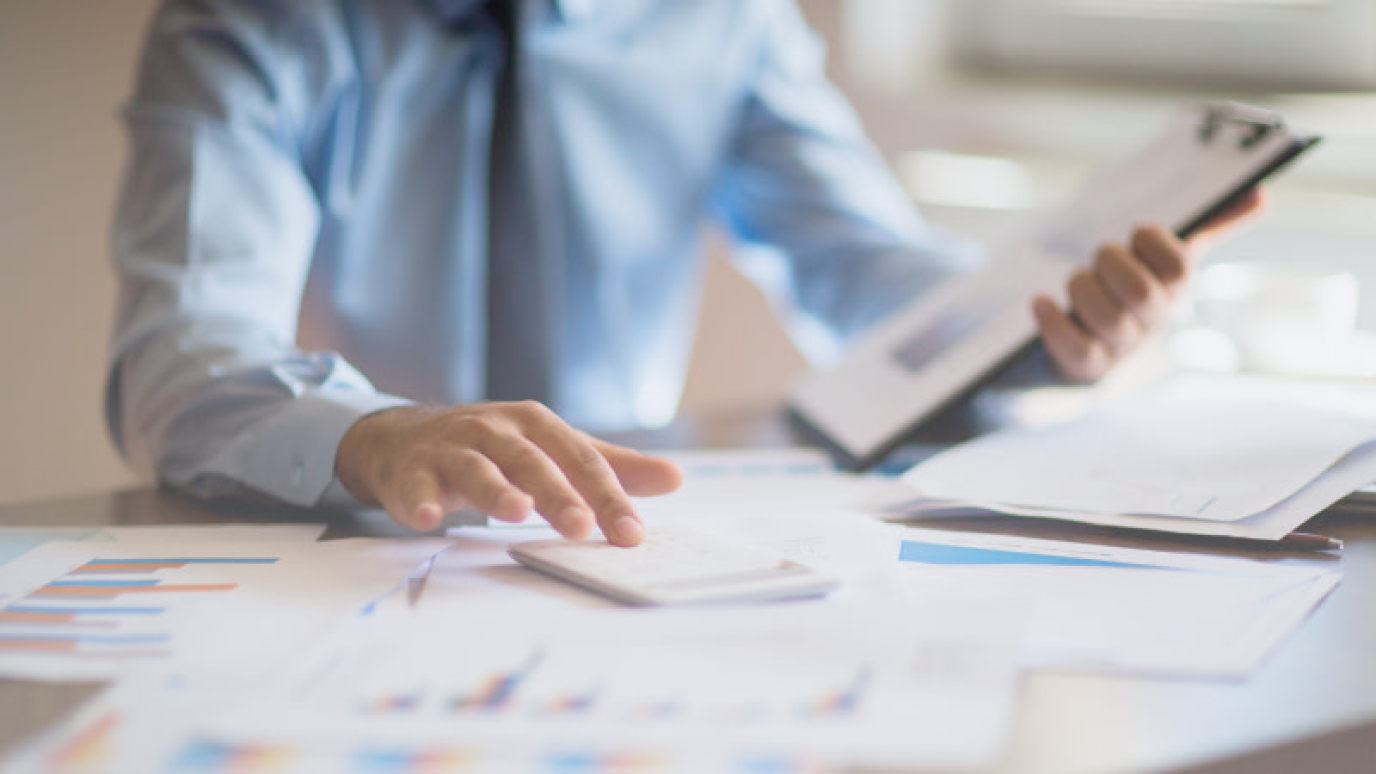 Man seated at table working with papers and a calculator
