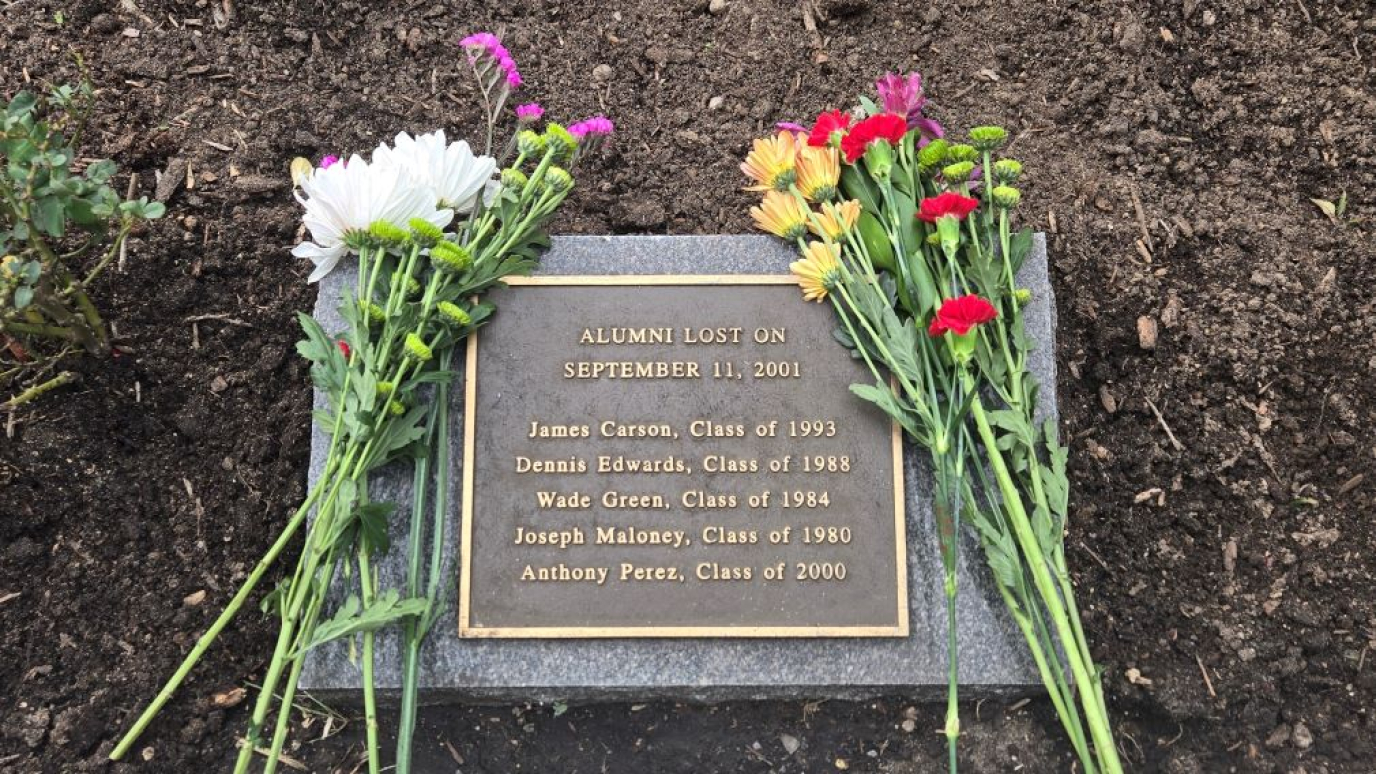 Monument with the five names and graduation years with fresh cut flowers draped across it