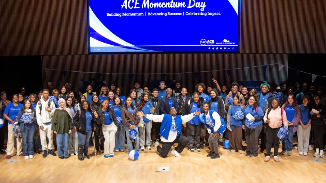 Group photo of a large, diverse group of students, most wearing blue ACE tee shirts, 