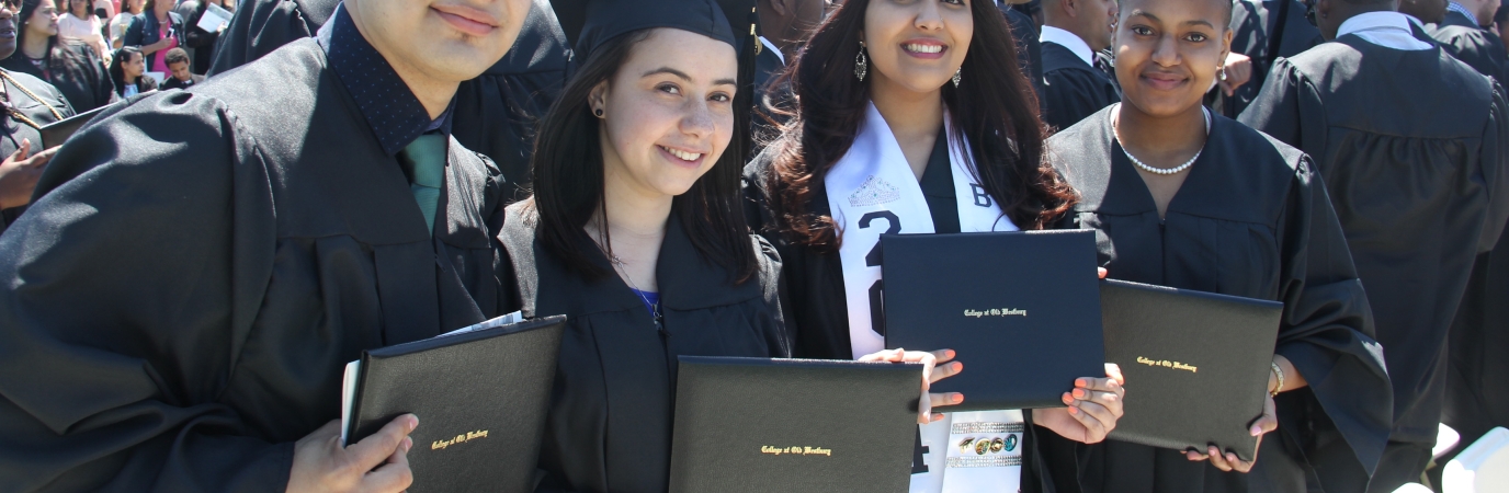 Four graduates in cap and gown at Commencement