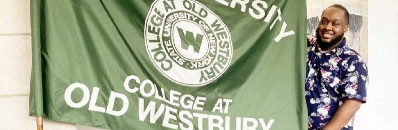 Kalief Metellus stands with the College flag that is on display in SUNY headquarters