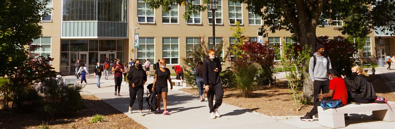 Students walking and sitting in front of the NAB on a sunny day