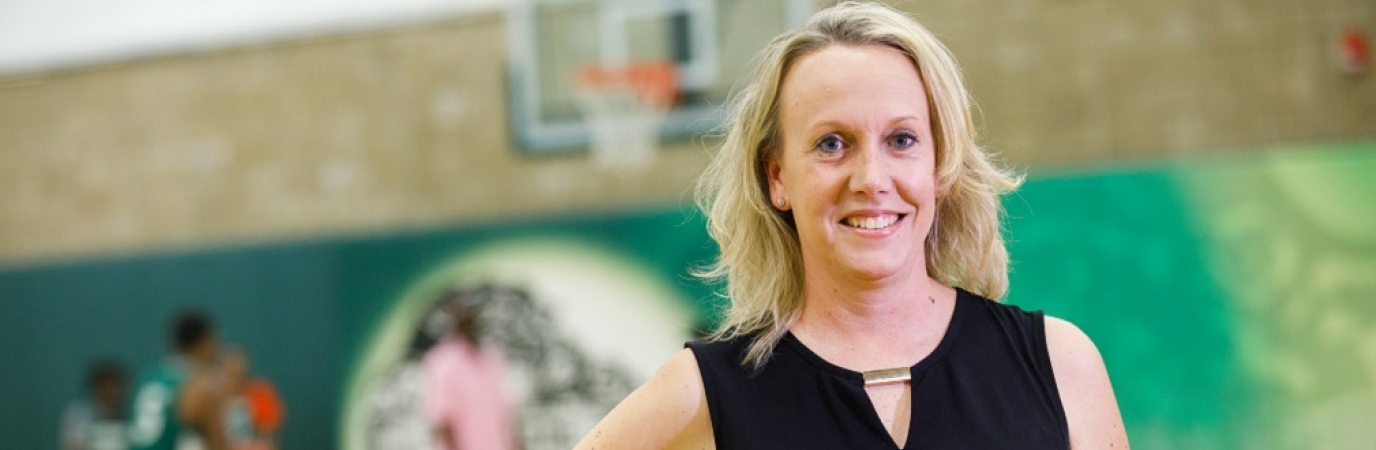 Lenore Walsh in black dress standing in Clark Center Fieldhouse